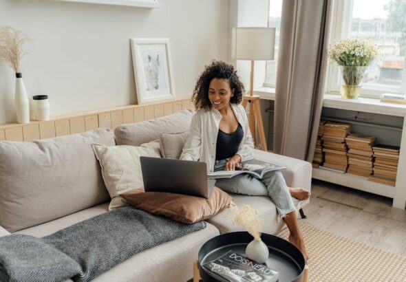 Free Woman in White Long Sleeve Using a Laptop while Sitting on a Sofa Stock Photo